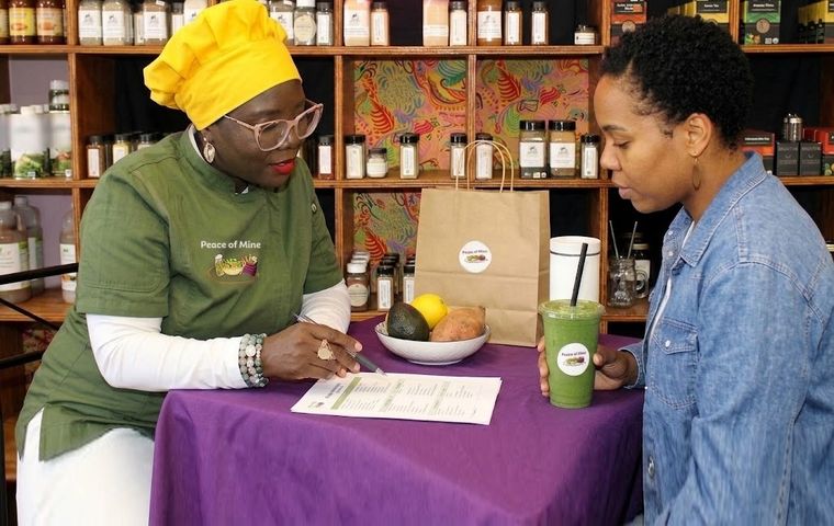 Chef Tatiana going over a nutrition plan with a client at a table in the shop